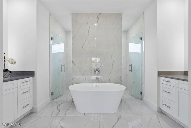 bathroom featuring marble finish flooring, baseboards, a soaking tub, and a marble finish shower