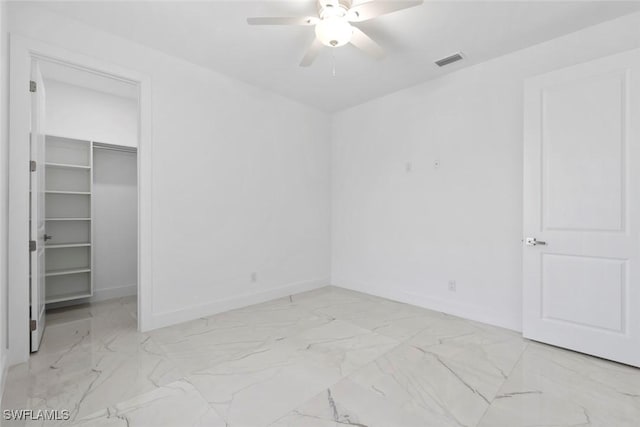 unfurnished bedroom with light marble finish flooring, baseboards, a walk in closet, and ceiling fan