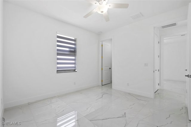 empty room with baseboards, light marble finish flooring, and a ceiling fan