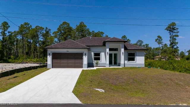 prairie-style home featuring stucco siding, a garage, french doors, driveway, and a front yard