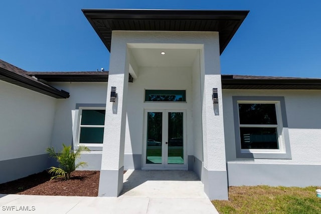 entrance to property featuring stucco siding and french doors
