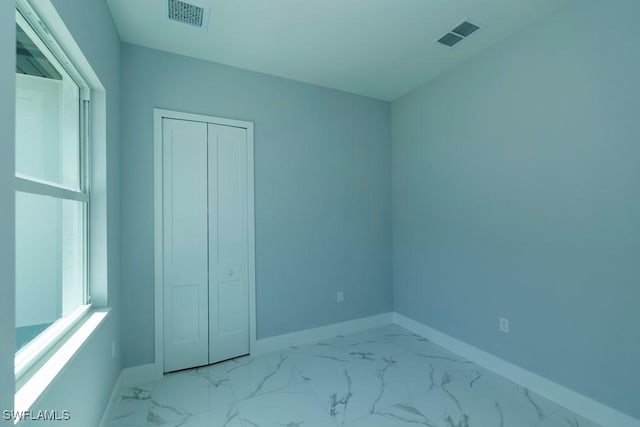 unfurnished room with baseboards and marble look tile flooring