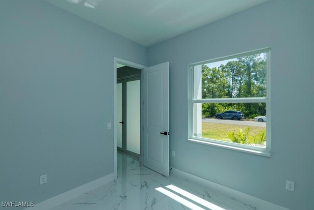 unfurnished room featuring baseboards and marble finish flooring