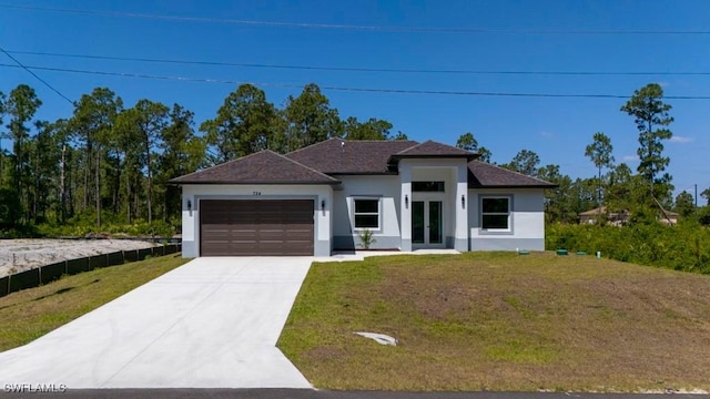 prairie-style house with stucco siding, an attached garage, driveway, and a front yard