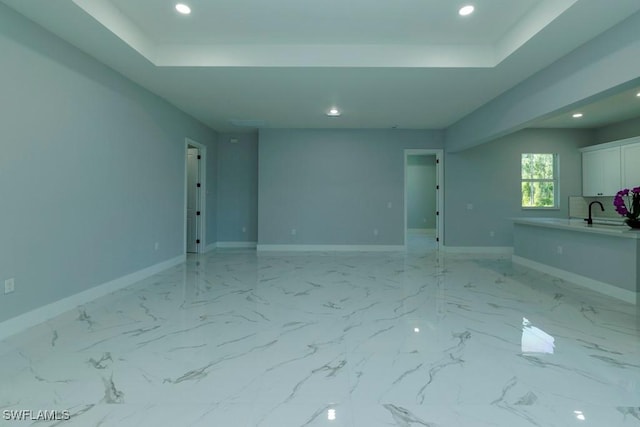 spare room featuring recessed lighting, baseboards, a tray ceiling, and a sink