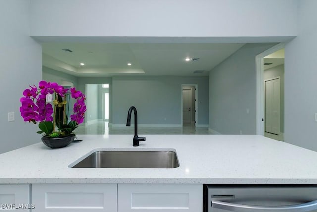 kitchen with dishwasher, a sink, white cabinets, light stone counters, and open floor plan