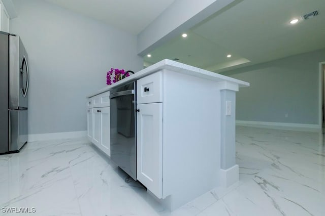 kitchen featuring freestanding refrigerator, recessed lighting, light marble finish floors, baseboards, and white cabinets