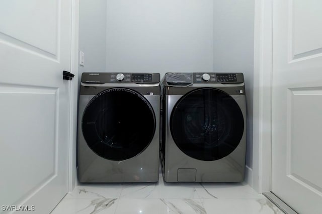 washroom featuring washing machine and clothes dryer and marble look tile flooring