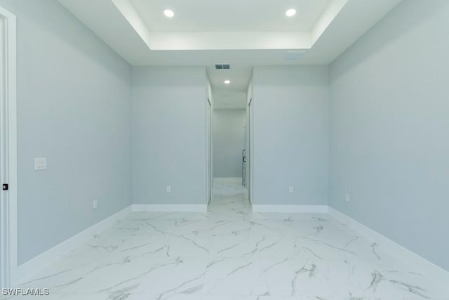 unfurnished bedroom featuring marble look tiles, recessed lighting, a tray ceiling, baseboards, and a spacious closet