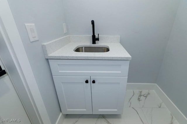 bathroom featuring marble finish floors, vanity, and baseboards