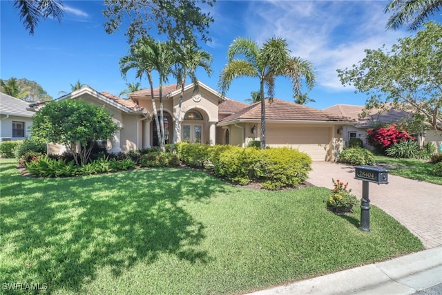 28404 Via Odanti Dr, Bonita Springs, FL 34135 - mediterranean / spanish-style house with an attached garage, a front lawn, stucco siding, decorative driveway, and a tiled roof