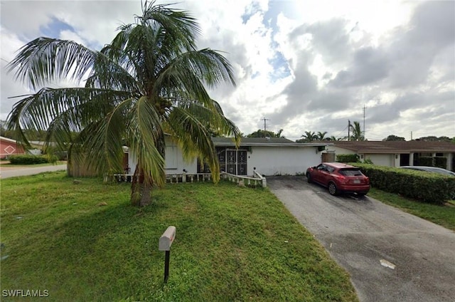 obstructed view of property with driveway and a front lawn