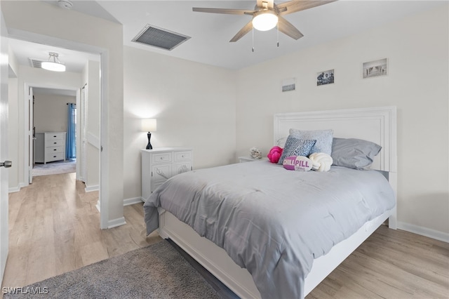bedroom with visible vents, a ceiling fan, baseboards, and wood finished floors