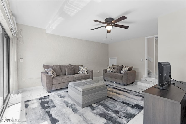 living area with baseboards, ceiling fan, and marble finish floor