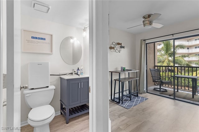 bathroom with a ceiling fan, toilet, a healthy amount of sunlight, and wood finished floors