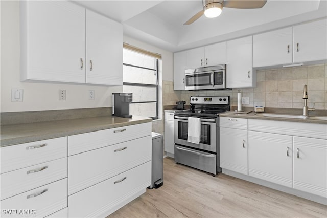 kitchen with ceiling fan, white cabinetry, tasteful backsplash, a sink, and appliances with stainless steel finishes
