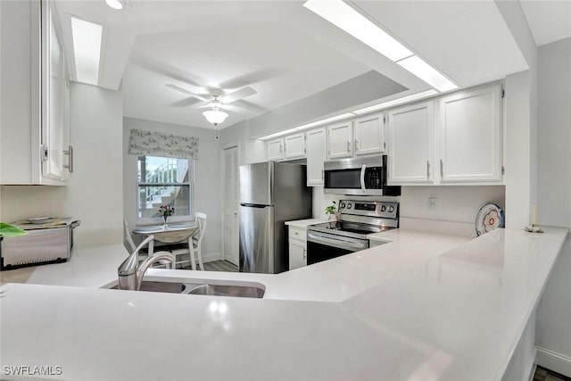 kitchen with a sink, light countertops, ceiling fan, and stainless steel appliances