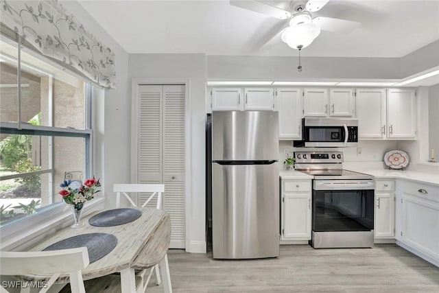 kitchen featuring white cabinets, appliances with stainless steel finishes, and a wealth of natural light