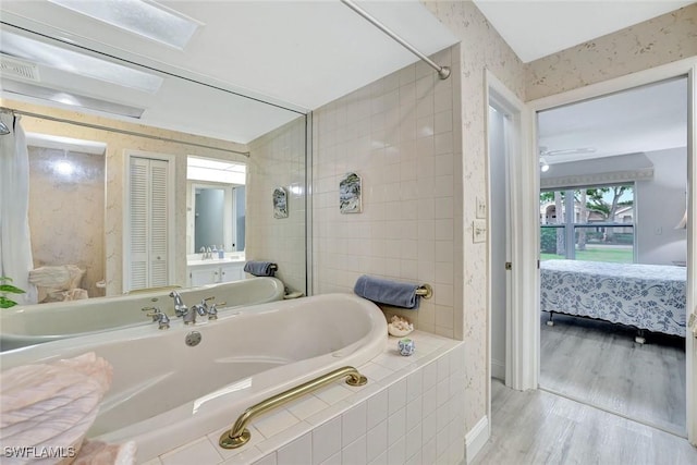 ensuite bathroom with a tile shower, wood finished floors, a closet, ensuite bathroom, and tiled bath