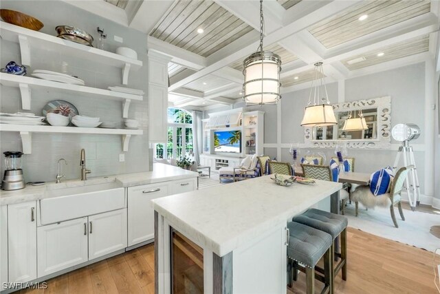 510 2nd St S Unit 102, Naples, FL 34102 - kitchen with coffered ceiling, light wood-style flooring, open shelves, tasteful backsplash, and a sink