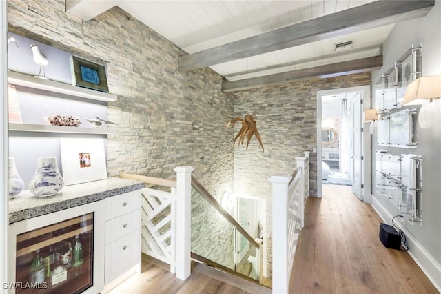 510 2nd St S Unit 102, Naples, FL 34102 - kitchen featuring beam ceiling, light wood-style flooring, white cabinets, light stone countertops, and wine cooler