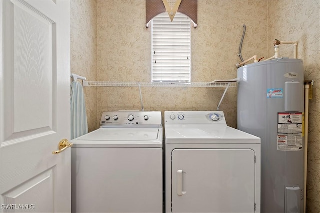 clothes washing area with electric water heater, washing machine and clothes dryer, wallpapered walls, and laundry area
