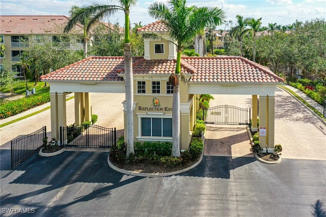 view of front of house featuring fence, a gate, a tiled roof, and stucco siding