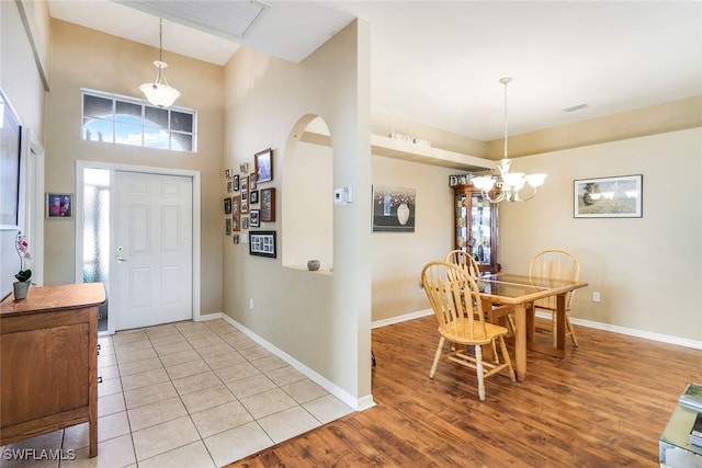 foyer featuring visible vents, arched walkways, baseboards, light wood finished floors, and an inviting chandelier