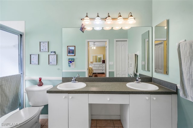 bathroom with a sink, tile patterned floors, toilet, and double vanity