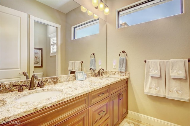 full bathroom with a sink, baseboards, toilet, and double vanity