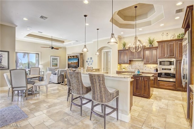 kitchen featuring visible vents, appliances with stainless steel finishes, a center island with sink, and a raised ceiling