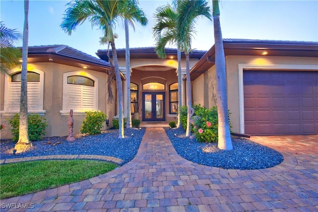 view of exterior entry featuring french doors, stucco siding, and driveway