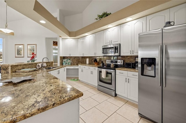 2536 SW 28th Pl, Cape Coral, FL 33914 - kitchen with a peninsula, light tile patterned flooring, dark stone counters, a sink, and appliances with stainless steel finishes
