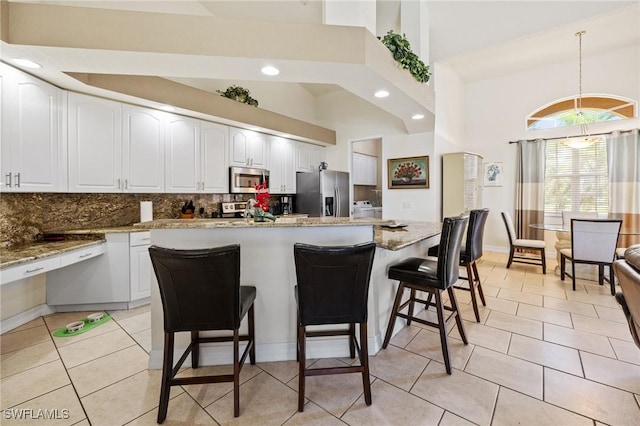 2536 SW 28th Pl, Cape Coral, FL 33914 - kitchen with decorative backsplash, stainless steel appliances, a kitchen bar, and a towering ceiling