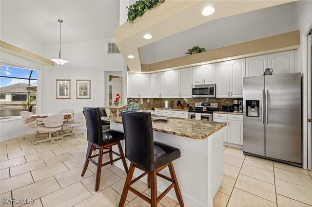 2536 SW 28th Pl, Cape Coral, FL 33914 - kitchen with a kitchen breakfast bar, stone countertops, stainless steel appliances, tasteful backsplash, and visible vents