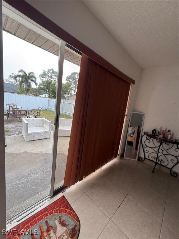 doorway to outside featuring tile patterned floors and a textured ceiling