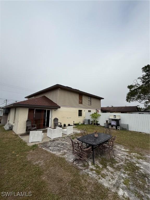 rear view of house with a sunroom, a patio area, fence, and central air condition unit