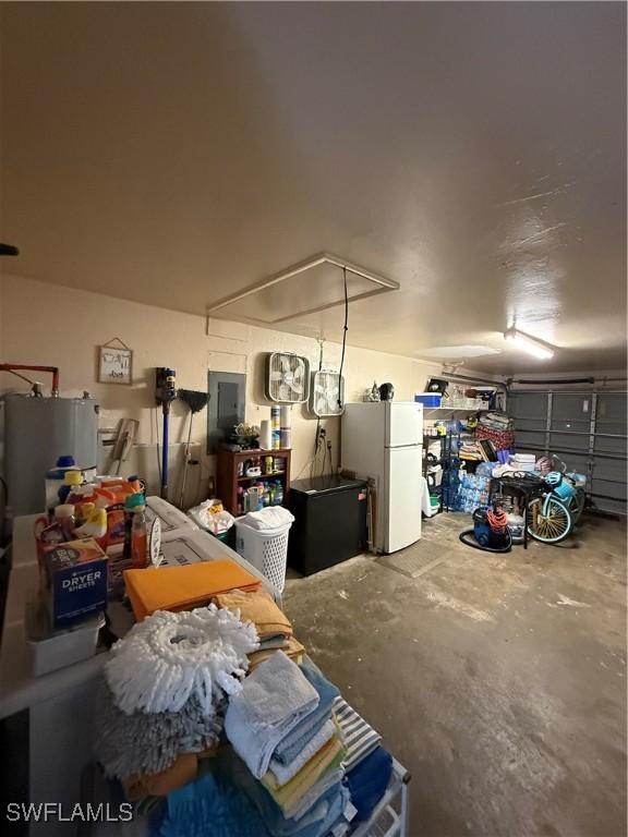 garage featuring gas water heater, freestanding refrigerator, and electric panel