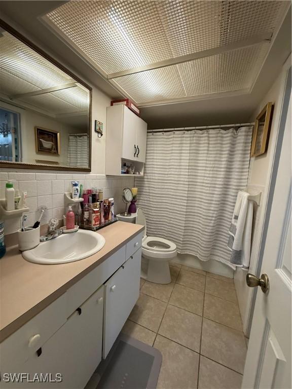 full bath with backsplash, shower / tub combo, tile patterned floors, vanity, and toilet
