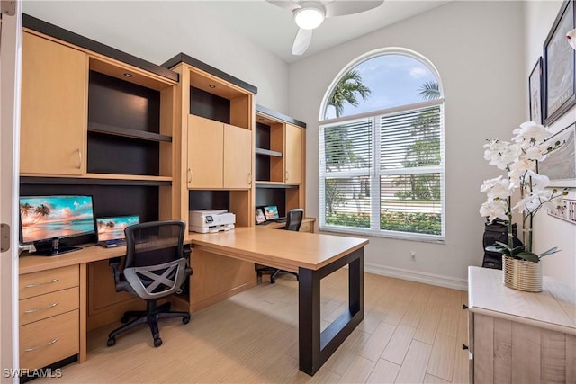 office area with ceiling fan, baseboards, built in desk, and light wood-style floors