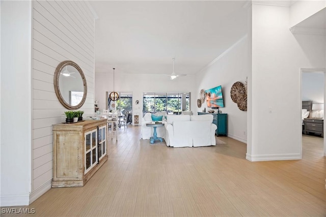 living area featuring light wood-type flooring, baseboards, and ornamental molding