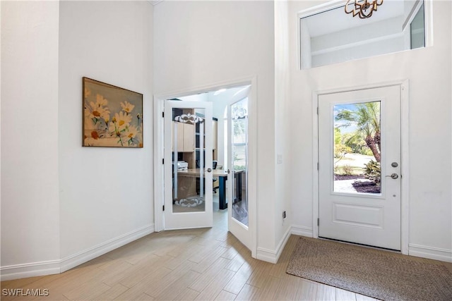 foyer entrance featuring a high ceiling, baseboards, french doors, and wood finished floors