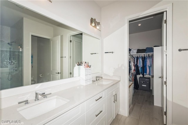 full bathroom with toilet, a shower with door, double vanity, and a spacious closet