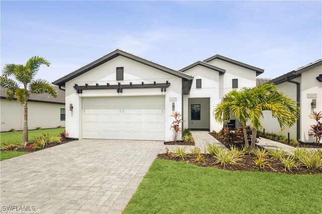 view of front of home featuring stucco siding, decorative driveway, a garage, and a front yard