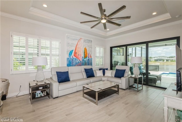 living area featuring a tray ceiling, a ceiling fan, light wood-type flooring, and crown molding