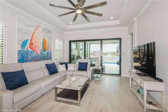 living area featuring plenty of natural light, a raised ceiling, a ceiling fan, and crown molding