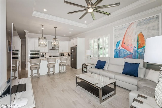 living room with a raised ceiling, ceiling fan, crown molding, a chandelier, and recessed lighting