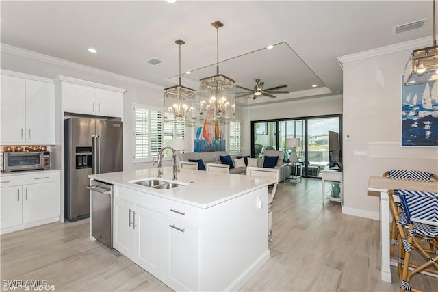 kitchen with appliances with stainless steel finishes, a sink, plenty of natural light, light countertops, and ornamental molding