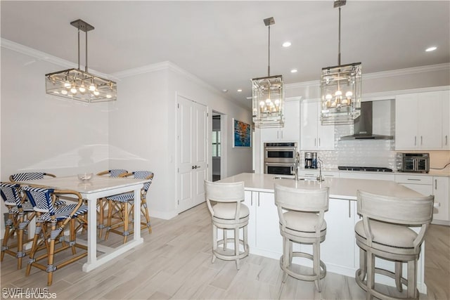 kitchen with wall chimney range hood, light countertops, decorative backsplash, white cabinetry, and recessed lighting
