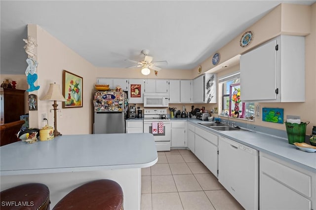kitchen featuring white appliances, a sink, ceiling fan, light tile patterned floors, and light countertops